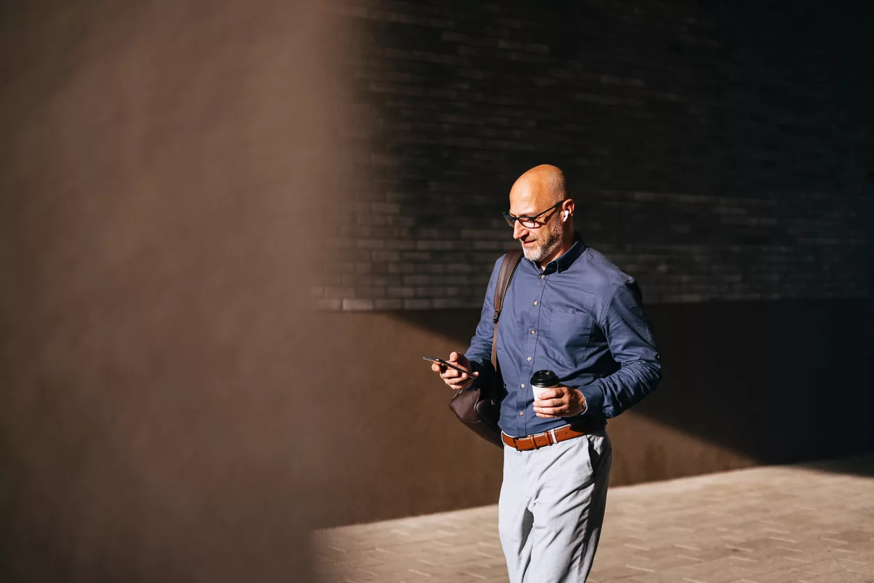 A busy man multitasks as he walks to work. West Avenue Private Wealth can take some of the stress off your plate by streamlining and focusing your complex financial situation.