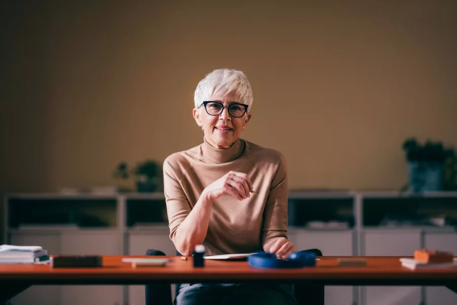 A middle-aged woman writes in a journal - maybe she's listing her needs for a financial plan, like the ones that West Avenue will curate for you.